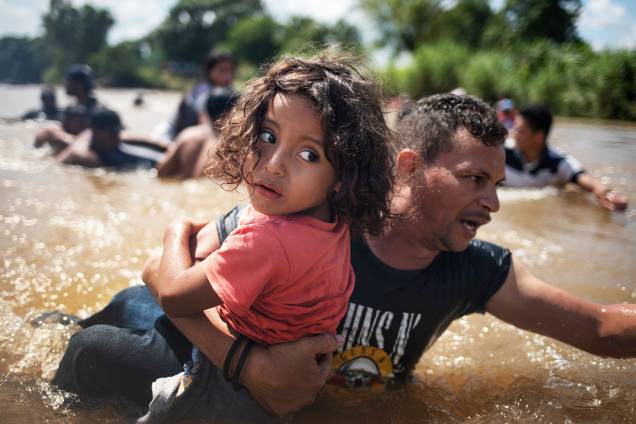 Pai carrega filho durante passagem pelo rio Suchiate, localizado na cidade mexicana de Ciudad Hidalgo, durante caravana de imigrantes da América Central, rumo aos Estados Unidos - 29/10/2018 Pai carrega filho durante passagem pelo rio Suchiate, localizado na cidade mexicana de Ciudad Hidalgo, durante caravana de imigrantes da América Central, rumo aos Estados Unidos - 29/10/2018