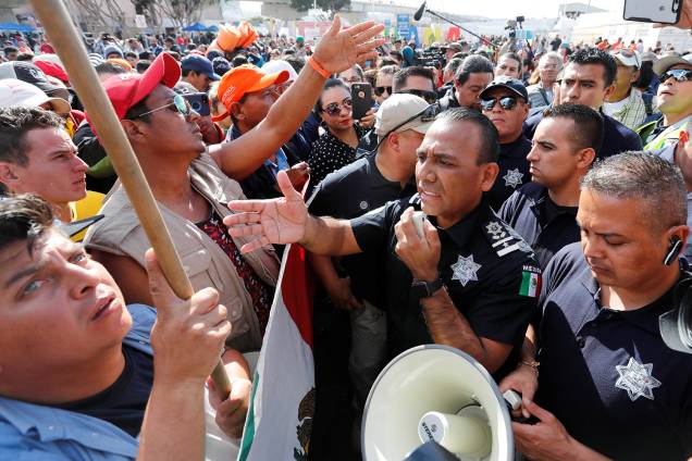 Migrantes negociam com policiais para atravessarem fronteira entre o México e os Estados Unidos, na cidade de Tijuana - 22/11/2018 Migrantes negociam com policiais para atravessarem fronteira entre o México e os Estados Unidos, na cidade de Tijuana - 22/11/2018