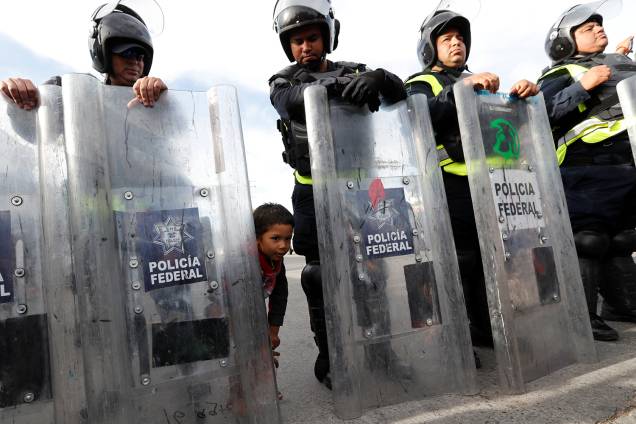 Criança é vista atrás de escudo de policial mexicano, próxima da fronteira entre o México e os Estados Unidos, na cidade de Tijuana - 22/11/2018 Criança é vista atrás de escudo de policial mexicano, próxima da fronteira entre o México e os Estados Unidos, na cidade de Tijuana - 22/11/2018