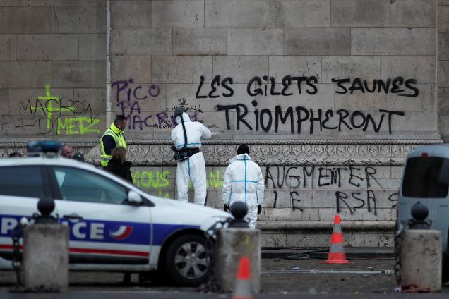 Policiais trabalham em torno da mensagem feita no Arco do Triunfo "Os coletes amarelos triunfarão", escrita durante as manifestações da última noite em Paris - 02/12/2018 Policiais trabalham em torno da mensagem feita no Arco do Triunfo "Os coletes amarelos triunfarão", escrita durante as manifestações da última noite em Paris - 02/12/2018