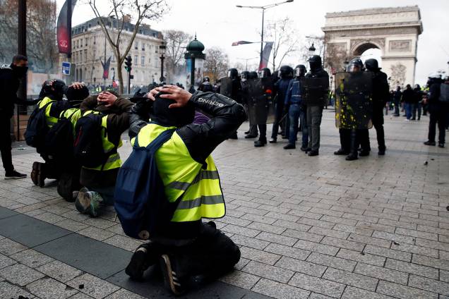 Manifestantes com coletes amarelos se ajoelham na Avenida Champs-Élysées próximo ao Arco do Triunfo e encara a Polícia francesa em Paris, França - 08/12/2018 Manifestantes com coletes amarelos se ajoelham na Avenida Champs-Élysées próximo ao Arco do Triunfo e encara a Polícia francesa em Paris, França - 08/12/2018