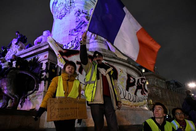 Manifestantes com coletes amarelos exibem cartazes e a bandeira da França durante protesto na Praça da República em Paris, França - 08/12/2018 Manifestantes com coletes amarelos exibem cartazes e a bandeira da França durante protesto na Praça da República em Paris, França - 08/12/2018