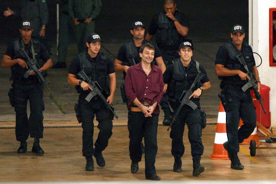O ex-ativista de extrema esquerda italiano Cesare Battisti, 52, é escoltado por policiais da Polícia Federal ao chegar em Brasília (DF). Battisti foi um dos chefes da organização de extrema esquerda Proletários Armados pelo Comunismo. Os assassinatos pelos quais foi condenado ocorreram em 1978 e 1979. Ele foi preso no Rio de Janeiro, onde estava desde 2004 - 19/03/2007 O ex-ativista de extrema esquerda italiano Cesare Battisti, 52, é escoltado por policiais da Polícia Federal ao chegar em Brasília (DF). Battisti foi um dos chefes da organização de extrema esquerda Proletários Armados pelo Comunismo. Os assassinatos pelos quais foi condenado ocorreram em 1978 e 1979. Ele foi preso no Rio de Janeiro, onde estava desde 2004 - 19/03/2007