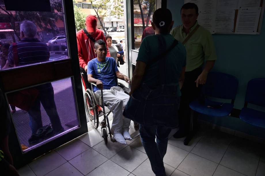 Parentes empurram um homem em uma cadeira de rodas em um clínica de tratamento para insuficiência renal estatal em Caracas, na Venezuela no terceiro do apagão que afeta praticamente toda a Venezuela - 10/03/2019