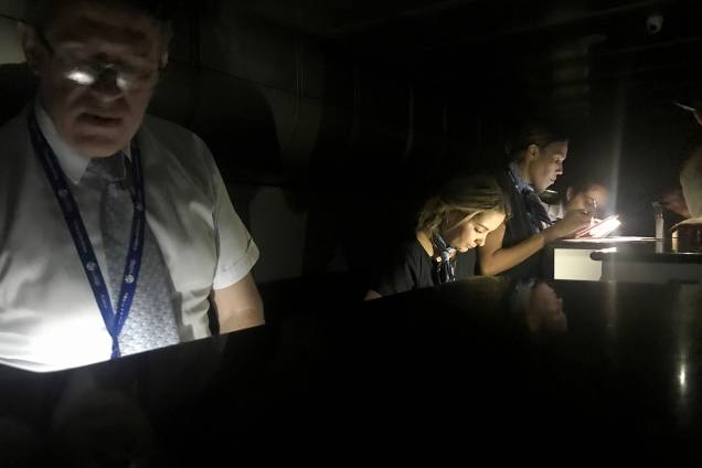 Funcionários conferem os cartões de embarque dos passageiros durante um blecaute no aeroporto internacional Simon Bolivar, em Caracas - 25/03/2019 Funcionários conferem os cartões de embarque dos passageiros durante um blecaute no aeroporto internacional Simon Bolivar, em Caracas - 25/03/2019
