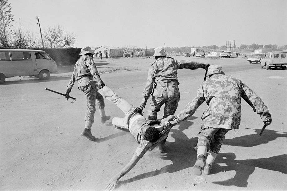 Policiais carregam manifestante anti-apartheid, durante protesto realizado em Soweto, na África do Sul - 15/06/1980