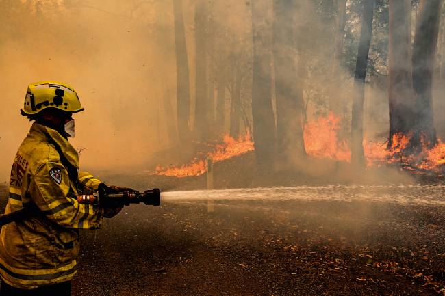 A Gloucester fire crew member fights flames from a bushfire at Koorainghat