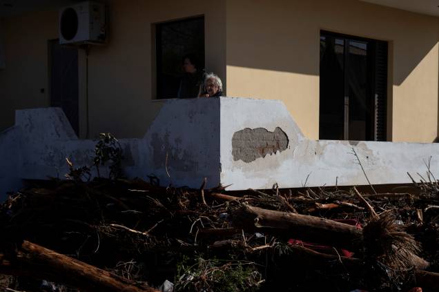 Moradores sentam-se na varanda, enquanto os detritos são recolhidos do lado de fora de suas casas após inundações na cidade de Kineta, Grécia — 25/11/2019 Moradores sentam-se na varanda, enquanto os detritos são recolhidos do lado de fora de suas casas após inundações na cidade de Kineta, Grécia — 25/11/2019