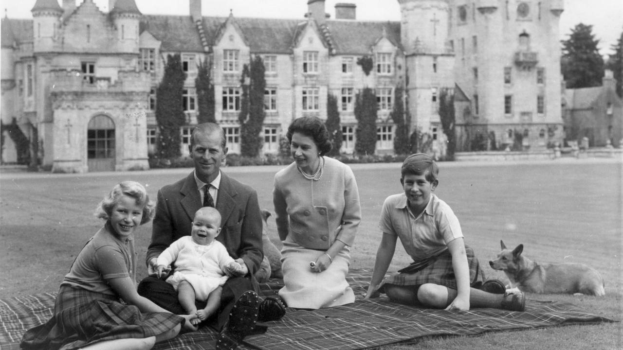9th September 1960: Queen Elizabeth II and Prince Philip, Duke of Edinburgh with their children, Prince Andrew (centre), Princess Anne (left) and Charles, Prince of Wales sitting on a picnic rug outside Balmoral Castle in Scotland. Queen Victoria's husband, Prince Albert, purchased Balmoral Castle in 1846, and the small castle which stood in the 7,000 hectare wooded estate was redeveloped in the 1850s.The granite building was designed by Aberdeen architect William Smith with suggestions from Albert himself, who decided the interior decoration should represent a Highland shooting box with tartan or thistle chintzes, and walls decorated with trophies and weapons. Queen Victoria often visited the Highlands with her family, especially after Albertfs death in 1861, and Balmoral is still a popular retreat for the present royal family. (Photo by Keystone/Getty Images)
