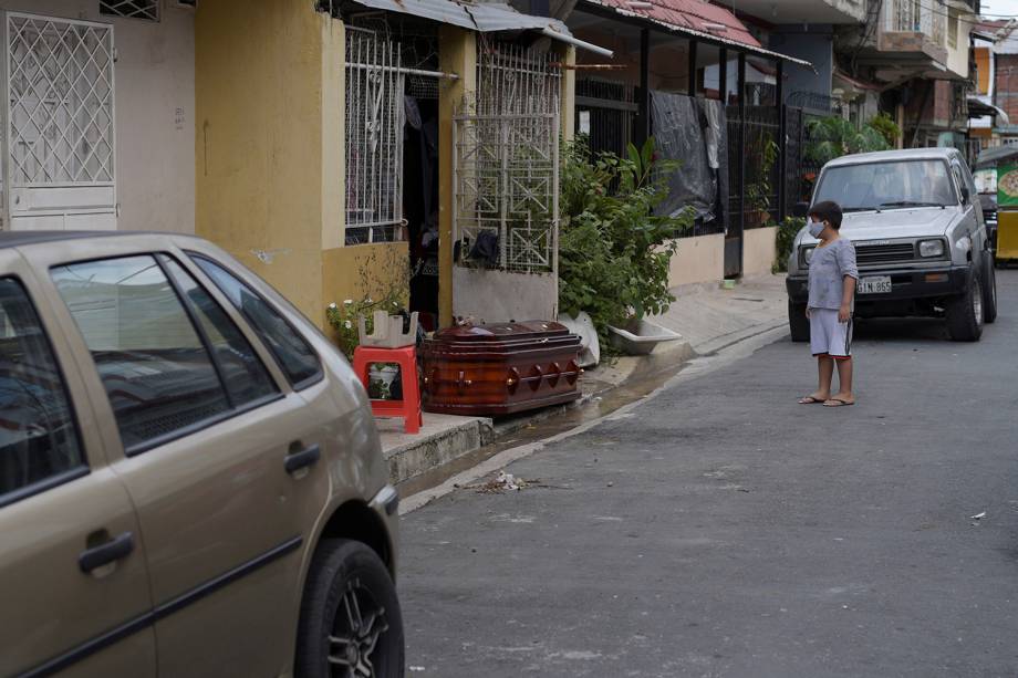 Uma criança observa um caixão com o corpo de uma pessoa que morreu em casa, durante o surto do coronavírus, em Guayaquil, no Equador