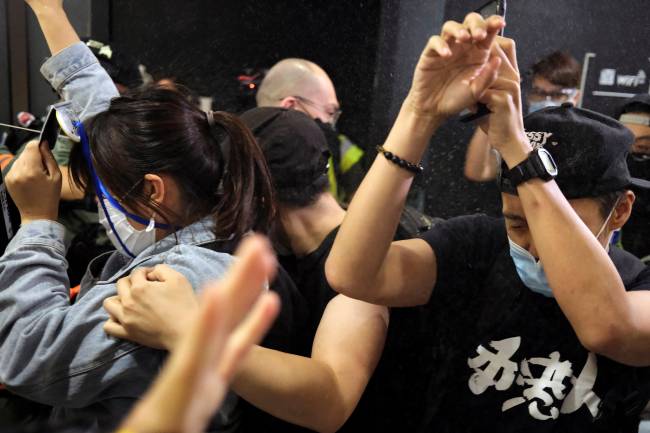 Anti-government protesters react as riot police disperse them with pepper spray during a rally inside a shopping mall, in Hong Kong
