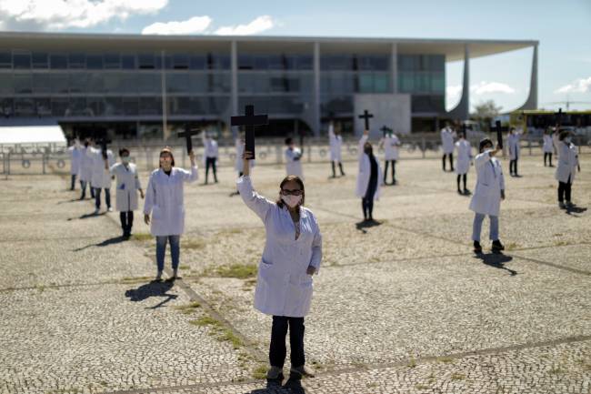 Nurses wearing protective face masks hold crosses during a symbolic protest and tribute for health workers on Labour Day, in Brasilia