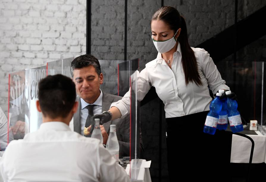 Garçonete serve clientes em Milão no primeiro dia de reabertura de restaurantes, bares e cafés na Itália - 18/05/2020