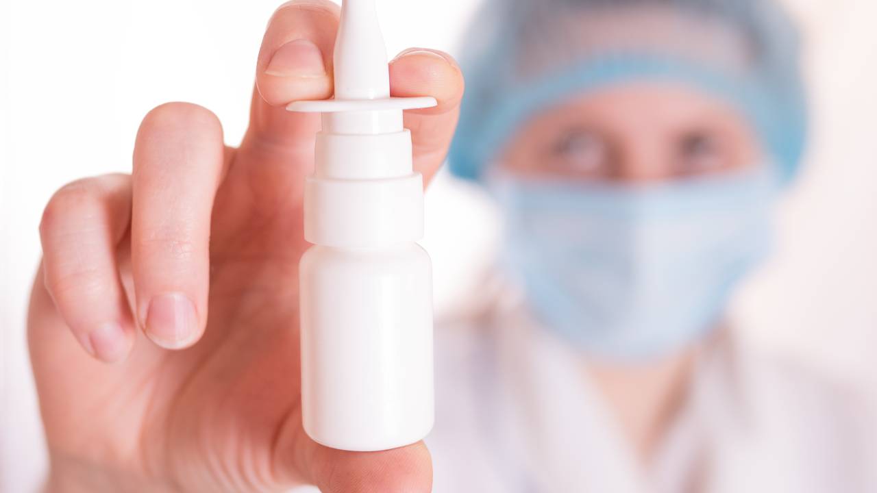 Nasal spray or drops for health in a white bottle, container in hand or palm from cold, flu, illness, runny nose. Pharmacy, care or treatment.