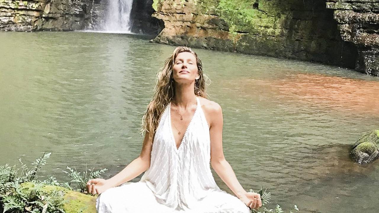Gisele Bündchen meditando perto de uma cahoeira