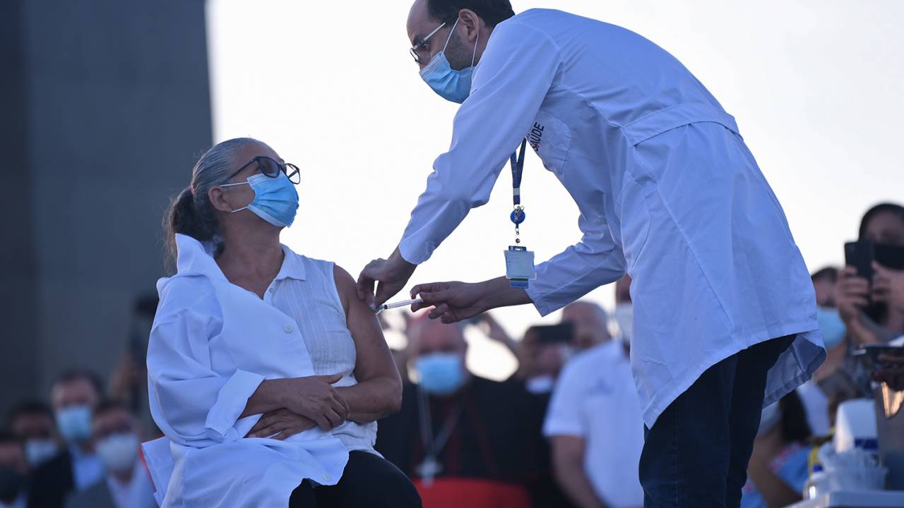 Dulcineia da Silva, 59, is inoculated with the Sinovac Biotech's CoronaVac vaccine against COVID-19 coronavirus at the Christ The Redeemer statue, on the Corcovado mountain in Rio de Janeiro, Brazil on January 18, 2021. (Photo by MAURO PIMENTEL / MAURO PIMENTEL / AFP)