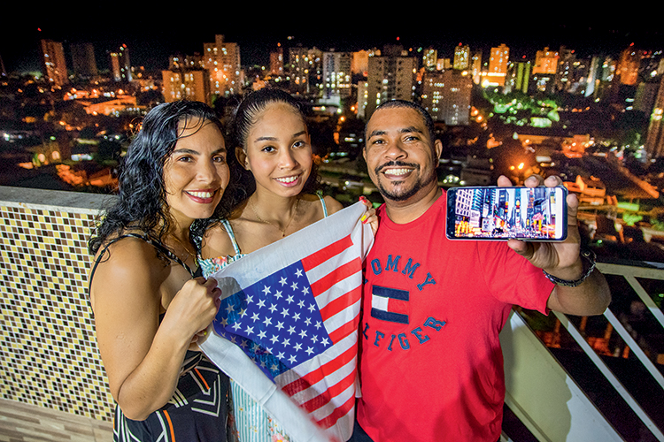 DE VALADARES A TIMES SQUARE - O vendedor Bruno, com a mulher Erica e a filha Bruna, exibe no celular o cartão-postal que tanto quer conhecer: “Vamos ter mais futuro lá e ainda ajudaremos a família”, planeja -