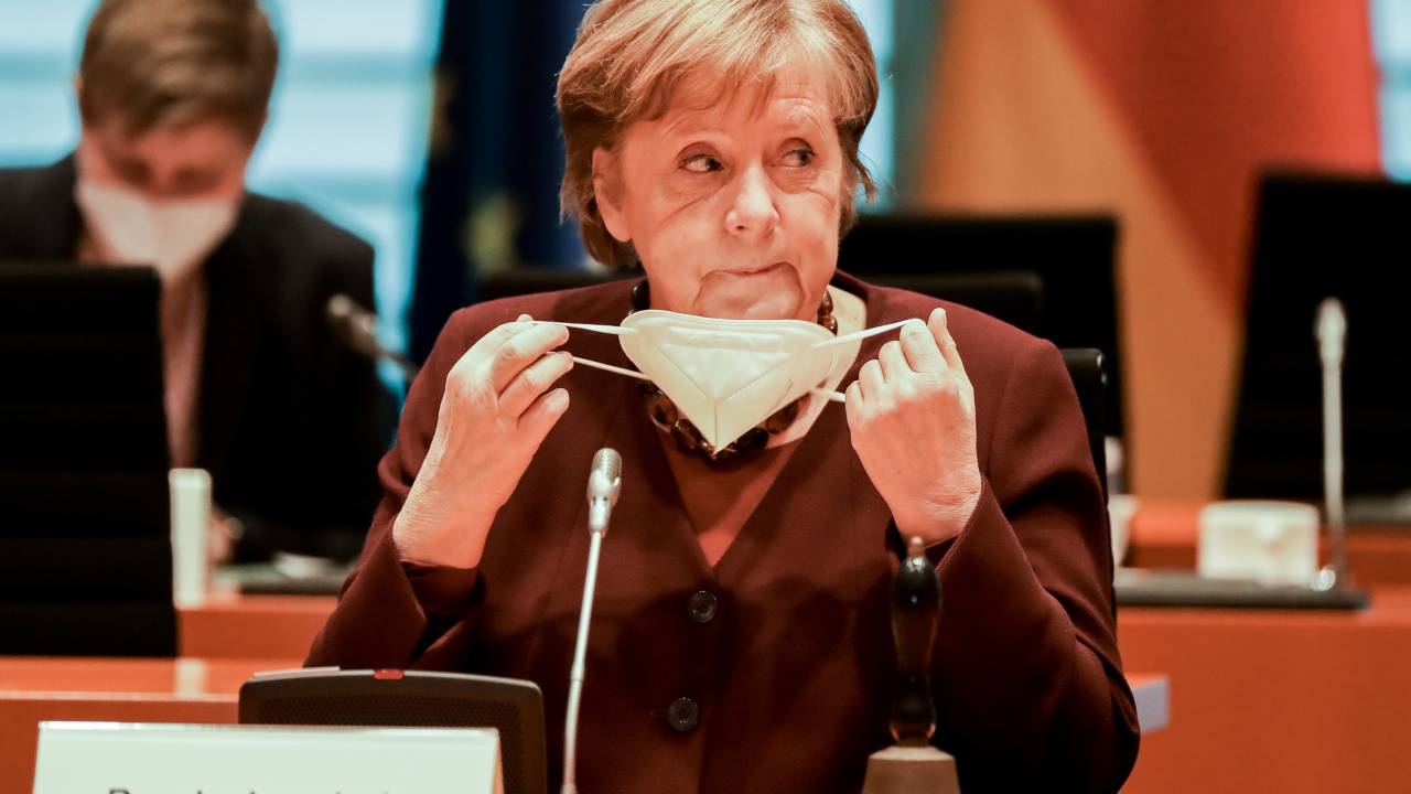 BERLIN, GERMANY - MARCH 10: German Chancellor Angela Merkel puts out a face mask as she attends the weekly meeting of the German Federal cabinet in the conference hall of the Chancellery on March 10, 2021 in Berlin, Germany. (Photo by Poly Styrene - Pool/Getty Images)