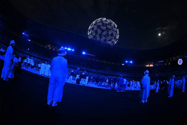 Atletas e voluntários olham drone no céu durante a cerimônia de abertura das Olimpíadas 2020, no Estádio Olímpico de Tóquio - Atletas e voluntários olham drone no céu durante a cerimônia de abertura das Olimpíadas 2020, no Estádio Olímpico de Tóquio -