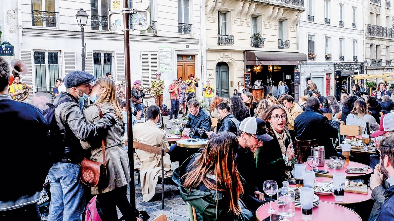 Parisienses tomam drinques em um bar no distrito de Montmartre