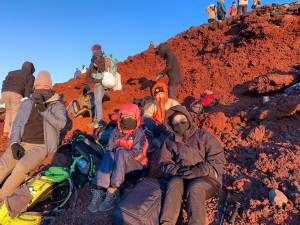 topo Tadashi, Erica, Max e Nina no topo do Monte Fuji, acompanhando o amanhecer -