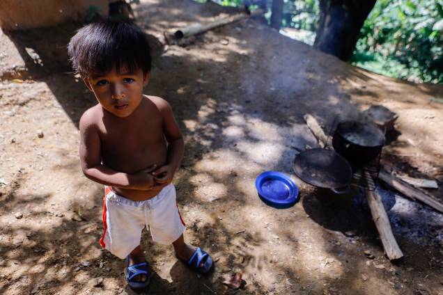 Uma criança espera que sua comida preparada em uma fogueira improvisada ao lado de sua casa, no bairro rural de Tocorón - Uma criança espera que sua comida preparada em uma fogueira improvisada ao lado de sua casa, no bairro rural de Tocorón -