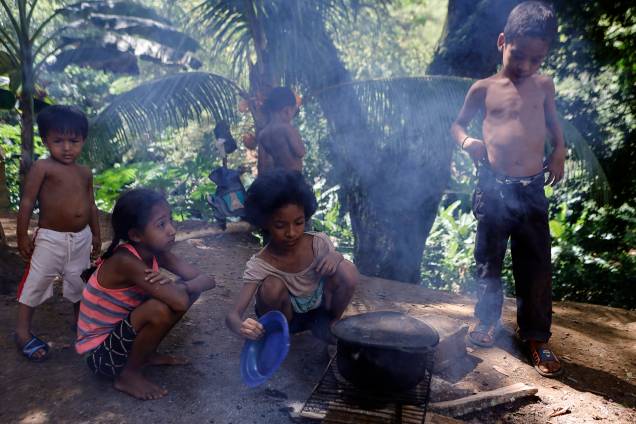Crianças cozinham em uma fogueira improvisada ao lado de sua casa no bairro rural de Tocorón, no estado de Miranda - Crianças cozinham em uma fogueira improvisada ao lado de sua casa no bairro rural de Tocorón, no estado de Miranda -