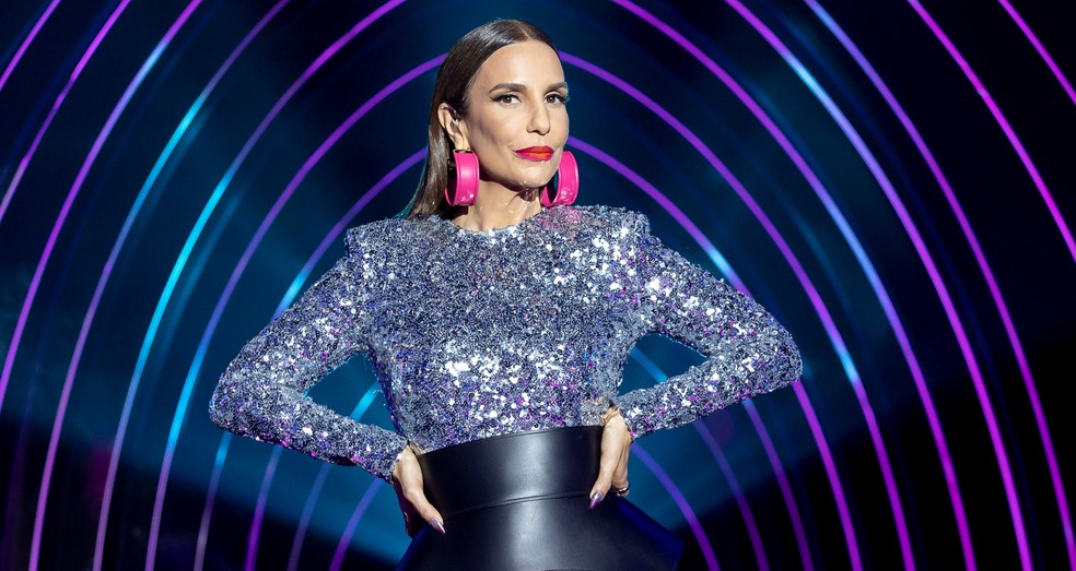 Ivete Sangalo de roupa prateada, com as mãos na cintura