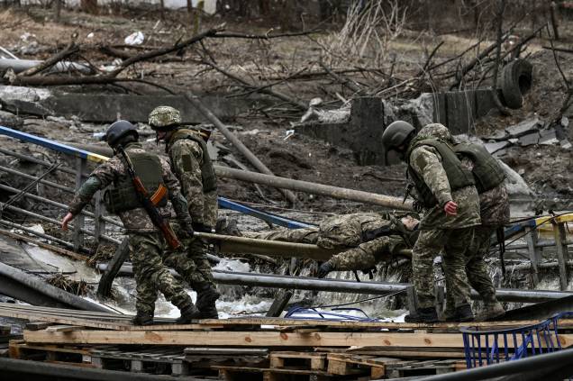 Militares ucranianos carregam o corpo de um companheiro em uma maca na cidade de Irpin - Militares ucranianos carregam o corpo de um companheiro em uma maca na cidade de Irpin -