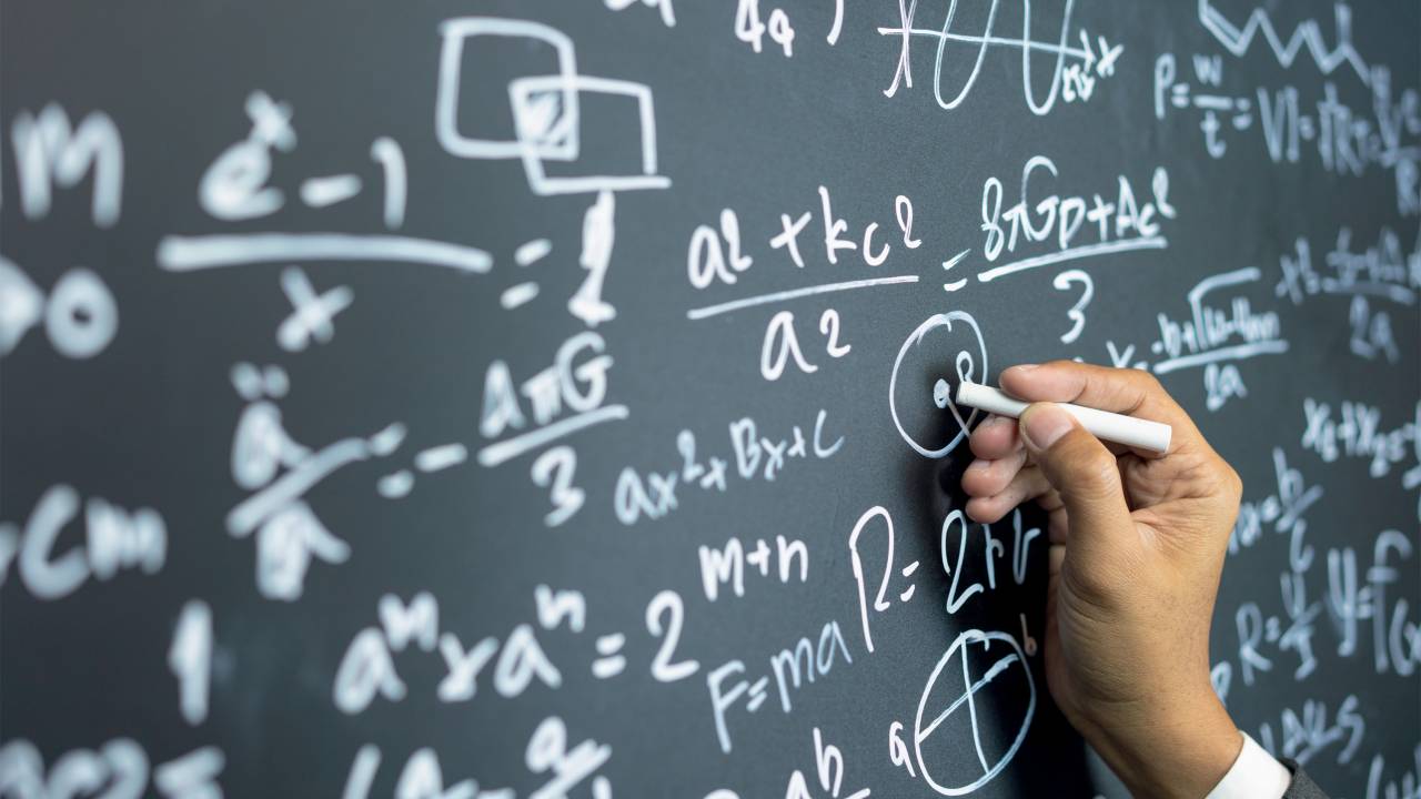 professor writing on the board while having a chalk and blackboard lecture (shallow DOF; color toned image)
