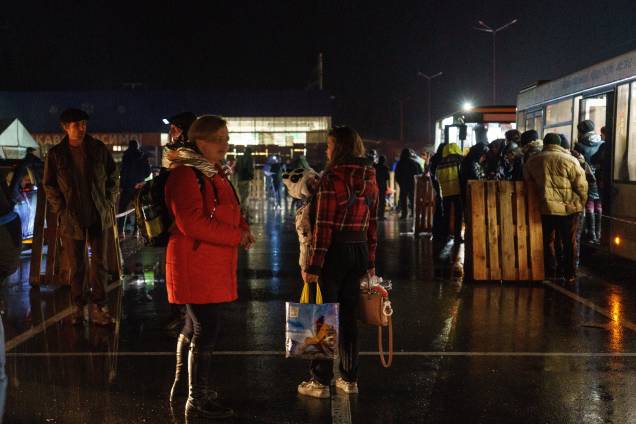 Pessoas aguardam ao lado de um ônibus enquanto um comboio de evacuação chega ao um centro de desalojados em Zaporizhzhia - Pessoas aguardam ao lado de um ônibus enquanto um comboio de evacuação chega ao um centro de desalojados em Zaporizhzhia -