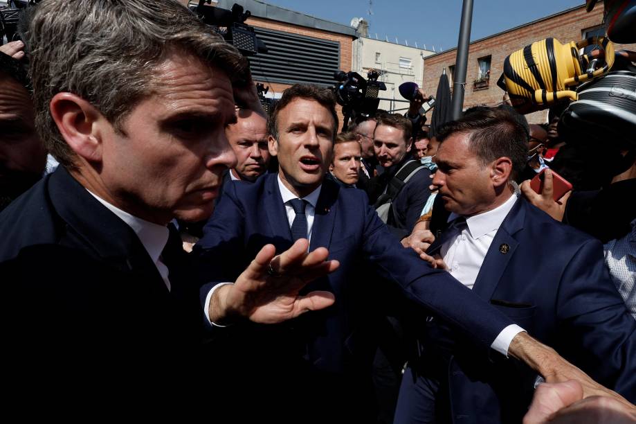 O presidente francês Emmanuel Macron com moradores, durante uma caminhada na praça do mercado Saint-Christophe em Cergy, subúrbio de Paris, França, 27 de abril de 2022. 