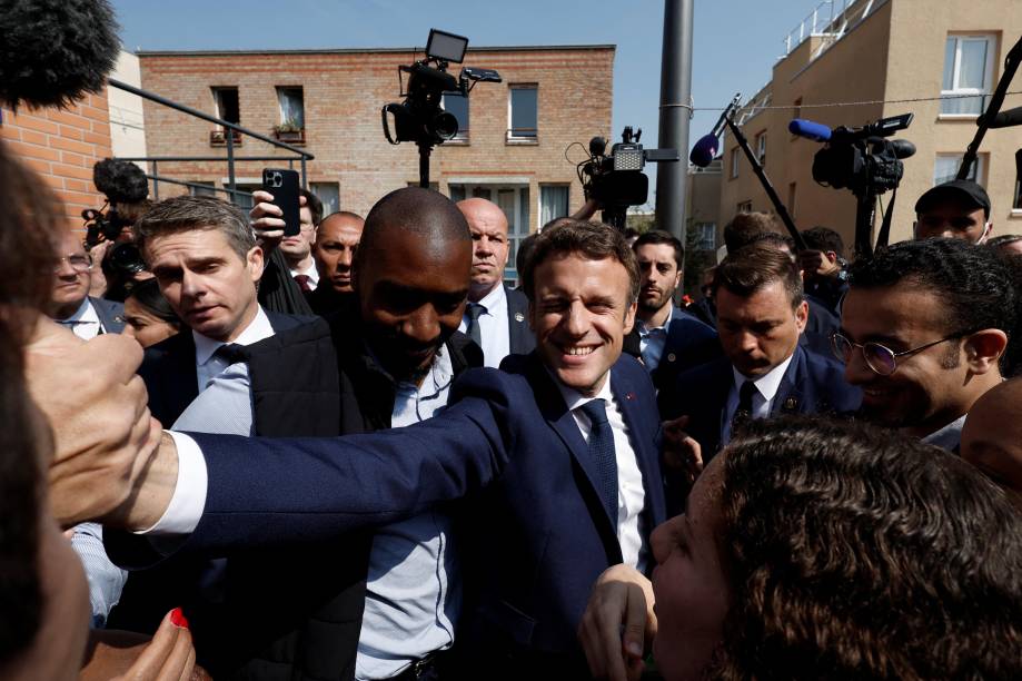 O presidente francês Emmanuel Macron com moradores, durante uma caminhada na praça do mercado Saint-Christophe em Cergy, subúrbio de Paris, França, 27 de abril de 2022. 