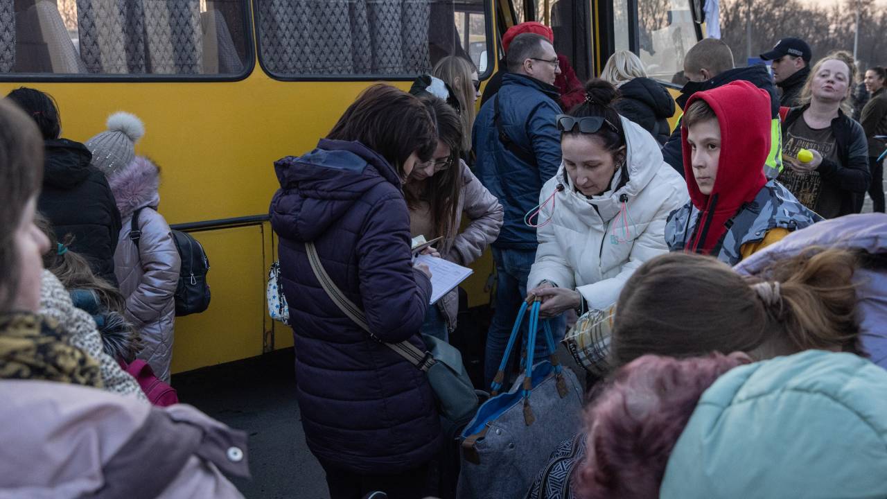 ZAPORIZHZHIA, UKRAINE - MARCH 25: People collect their belongings after getting off a bus that arrived with a large convoy of cars and buses at an evacuation point, carrying hundreds of people evacuated from Mariupol and Melitopol on March 25, 2022 in Zaporizhzhia, Ukraine. Tens of thousands of people remain trapped in Mariupol, a port city that has faced weeks of heavy bombardment by Russian forces. (Photo by Chris McGrath/Getty Images)