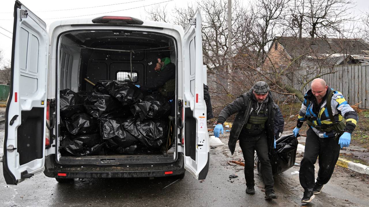 EDITORS NOTE: Graphic content / CAPTION ADDITION - Communal workers carry a body of a civilian man in the town of Bucha, not far from the Ukrainian capital of Kyiv on April 3, 2022. US and NATO leaders voiced shock and horror at new evidence of atrocities against civilians in Ukraine, and warned that Russian troop movements away from Kyiv did not signal a withdrawal or end to the violence. - The Kremlin on April 4, 2022 rejected accusations that Russian forces were responsible for killing civilians near Kyiv. "We categorically reject all allegations," Kremlin spokesman Dmitry Peskov told journalists. (Photo by Sergei SUPINSKY / AFP)