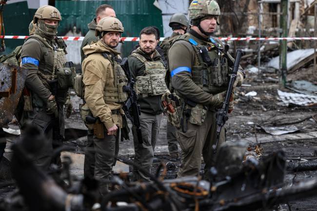 UKRAINE-RUSSIA-CONFLICT President Volodymyr Zelensky (C) walks in the town of Bucha, just northwest of the Ukrainian capital Kyiv on April 4, 2022. - Ukraine's President Volodymyr Zelensky said on April 3, 2022 the Russian leadership was responsible for civilian killings in Bucha, outside Kyiv, where bodies were found lying in the street after the town was retaken by the Ukrainian army. (Photo by RONALDO SCHEMIDT / AFP)