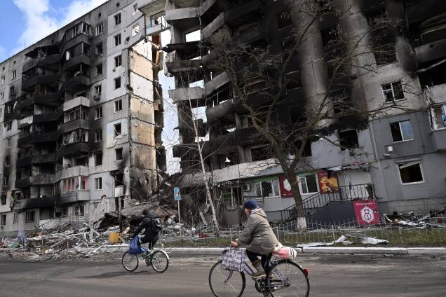 Pessoas andam de bicicleta passando por prédios destruídos na cidade de Borodianka, a noroeste de Kiev - Pessoas andam de bicicleta passando por prédios destruídos na cidade de Borodianka, a noroeste de Kiev -