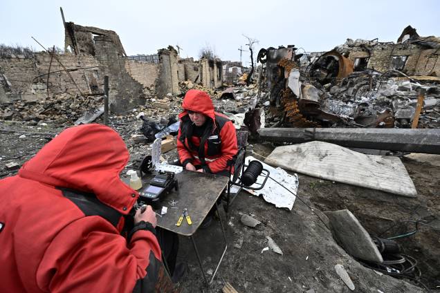 Reparadores restauram cabos de comunicação local entre os destroços de veículos blindados e edifícios destruídos em uma rua na cidade de Bucha, nos arredores da capital ucraniana Kiev - Reparadores restauram cabos de comunicação local entre os destroços de veículos blindados e edifícios destruídos em uma rua na cidade de Bucha, nos arredores da capital ucraniana Kiev -