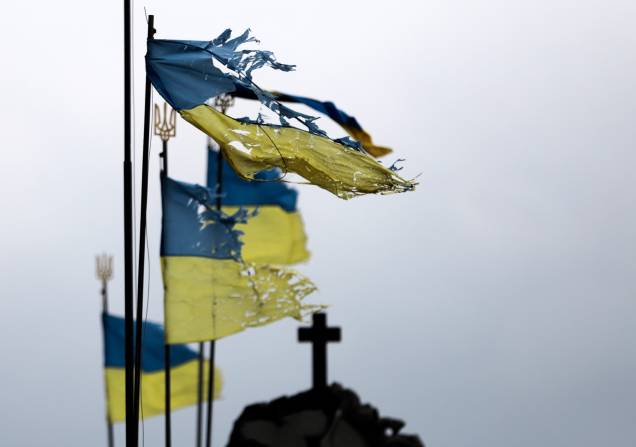 Bandeiras nacionais danificadas tremulam ao vento em um cemitério da cidade de Chernihiv que foi bloqueada por muito tempo pelas tropas russas - Bandeiras nacionais danificadas tremulam ao vento em um cemitério da cidade de Chernihiv que foi bloqueada por muito tempo pelas tropas russas -