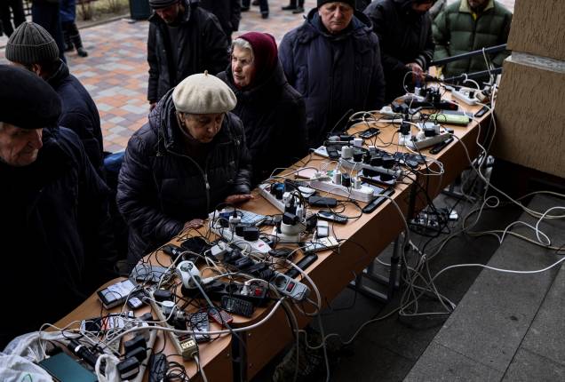Pessoas carregando os seus celulares em um prédio público de Bucha - Pessoas carregando os seus celulares em um prédio público de Bucha -