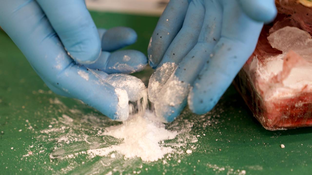 24 February 2022, Hamburg: A press officer of the Hamburg Customs presents a small part of the seized cocaine at a media event in the port. Customs seized more than 2.6 tons of cocaine in the port of Hamburg. The narcotic was hidden in a sea container behind two pallets of bananas. The container from Ecuador had already been unloaded on Christmas Eve and had been standing at a container terminal in the port ever since. The long standing time also made customs curious. Customs officials took the box to X-ray inspection at the container inspection facility of the customs office in Waltershof, where the narcotics with an approximate retail value of 350 million euros were then discovered. Photo: Marcus Brandt/dpa (Photo by Marcus Brandt/picture alliance via Getty Images)