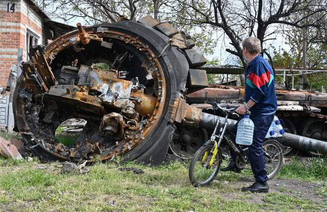 Um morador local, observa um tanque russo destruído ao lado de uma casa residencial na vila de Mala Rogan, a leste de Kharkiv, em 15 de maio de 2022, em meio à invasão russa da Ucrânia. Um morador local, observa um tanque russo destruído ao lado de uma casa residencial na vila de Mala Rogan, a leste de Kharkiv, em 15 de maio de 2022, em meio à invasão russa da Ucrânia.