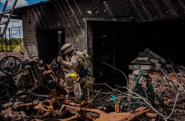 Um soldado da unidade de forças especiais ucranianas, passa por destroços na aldeia de Rus'ka Lozova, ao norte de Kharkiv, em 16 de maio de 2022. Um soldado da unidade de forças especiais ucranianas, passa por destroços na aldeia de Rus'ka Lozova, ao norte de Kharkiv, em 16 de maio de 2022.