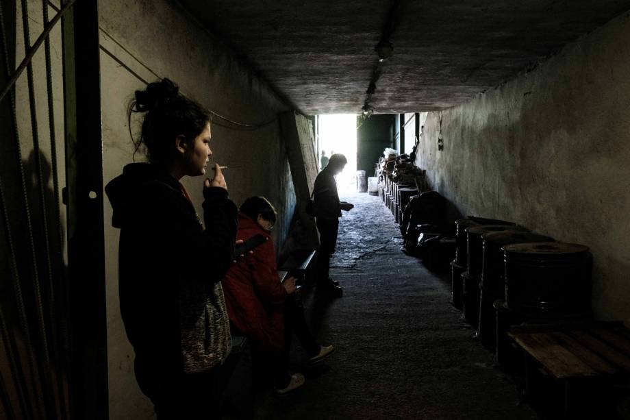 Uma mulher fumando um cigarro na entrada do bunker da fábrica Ostchem em Severodonetsk, leste da Ucrânia, em 27 de abril de 2022, em meio à invasão russa da Ucrânia.