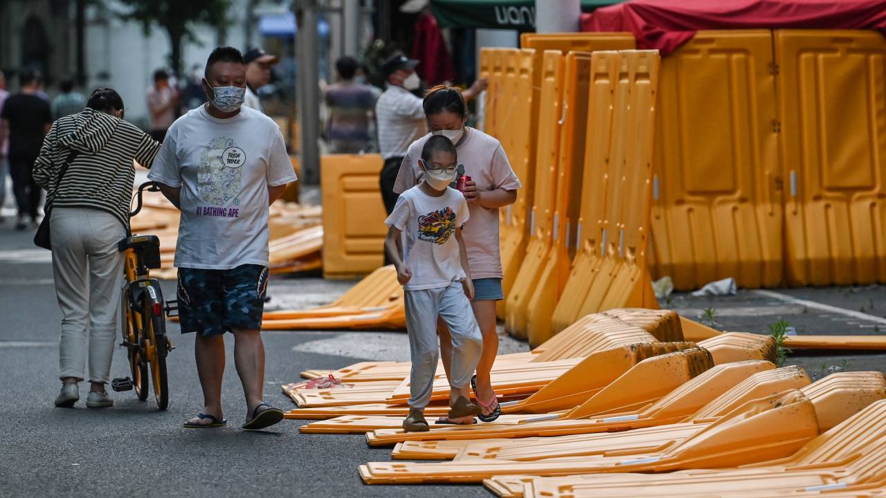 A boy runs over barriers, erected on March 19 according to local residents as part of pandemic lockdowns in the area and taken down earlier this afternoon, in the Jing' an district of Shanghai on May 31, 2022, as the city prepares to lift more curbs after two months of heavy-handed restrictions. (Photo by Hector RETAMAL / AFP)