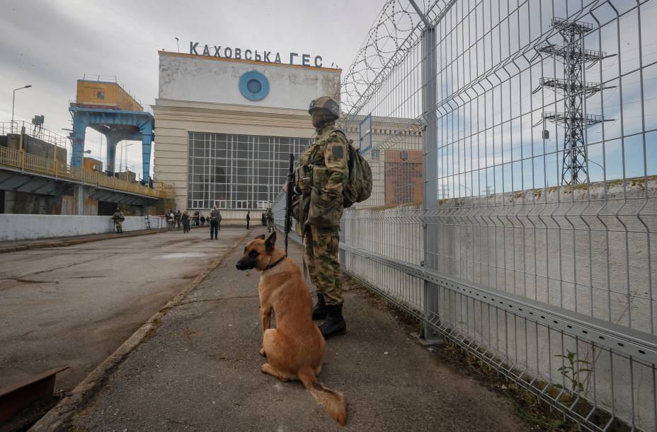 Um soldado russo e um cão de guarda perto da Usina Hidrelétrica Kakhovka no rio Dnieper em Kakhovka, próximo de Kherson, Ucrânia, em 20 de maio de 2022.