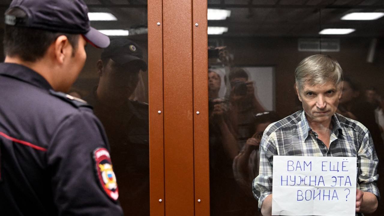 Moscow city deputy Alexei Gorinov, accused of spreading "knowingly false information" about the Russian army fighting in Ukraine, stands with a poster reading ""Do you still need this war?" inside a glass cell during the vedict hearing in his trial at a courthouse in Moscow on July 8, 2022. (Photo by Kirill KUDRYAVTSEV / AFP)