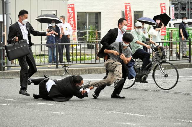JAPAN-POLITICS-ATTACK-ABE This image received from the Asahi Shimbun newspaper shows a man (centre R) suspected of shooting former Japanese prime minister Shinzo Abe being tackled to the ground by police at Yamato Saidaiji Station in the city of Nara on July 8, 2022. - Abe was pronounced dead on July 8, the hospital treating him confirmed, after he was shot at a campaign event in the city of Nara. (Photo by ASAHI SHIMBUN / AFP) / Japan OUT - NO Internet / NO ARCHIVES