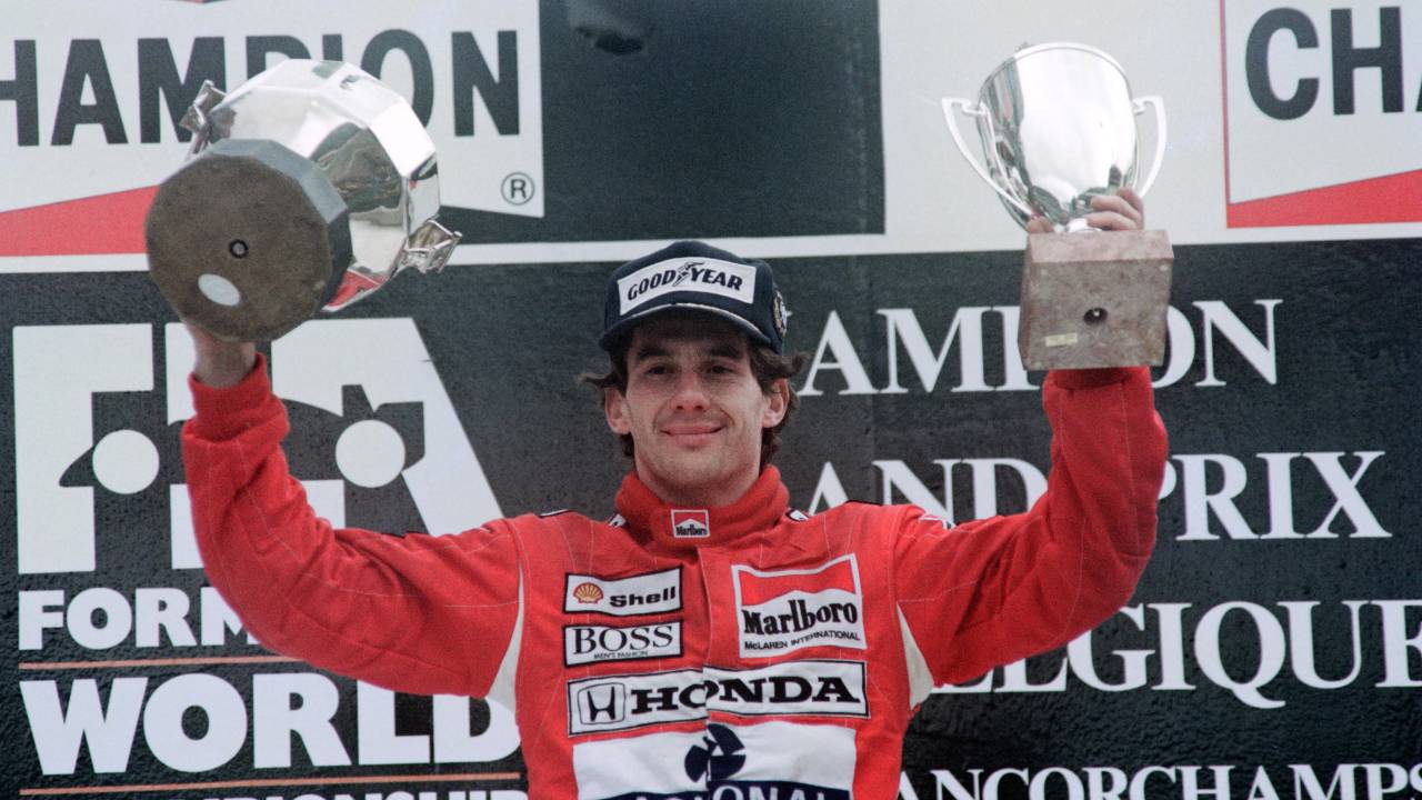 Brazilian defending World champion Ayrton Senna holding his trophy aloft, waves to the crowd after his victory in the Belgian Formula One Grand Prix on August 27, 1989. (Photo by Jean-Loup GAUTREAU and Pascal PAVANI / AFP)