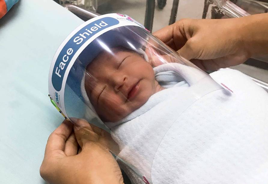 Hospital Samutprakarn, uma enfermeira ajusta o protetor facial em um bebê recém-nascido para proteger do novo coronavírus no berçário do hospital na província de Samutprakarn, centro da Tailândia. 03/04/2020